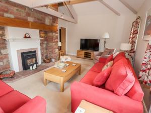 a living room with red couches and a fireplace at Edencroft in Penrith
