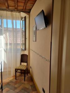 a room with a tv and a chair and a window at B&B Baldovino di Monte in Monte San Savino