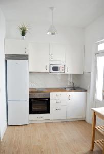 cocina con armarios blancos, fregadero y microondas en Apartamento en centro de Ferrol, en Ferrol