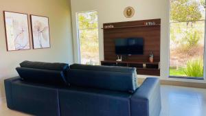 ein Wohnzimmer mit einem blauen Sofa und einem Flachbild-TV in der Unterkunft Casa Lago de Furnas in Capitólio