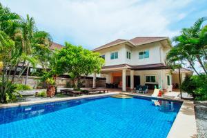 a villa with a swimming pool in front of a house at Captivating 3-Bed Villa in Muang Pattaya in Nong Prue