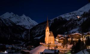 uma igreja na neve à noite com montanhas em Ferienwohnung Alex em Heiligenblut