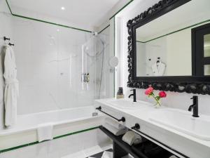 a white bathroom with a sink and a mirror at H10 Casa de la Plata in Seville