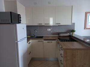 a kitchen with a white refrigerator and a sink at Apartman BoloB in Baška