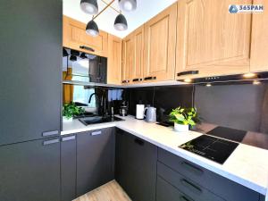 a kitchen with wooden cabinets and black appliances at Apartamenty Na Fali w Gąskach - 365PAM in Gąski