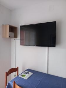 Habitación con mesa y TV en la pared. en Apartman BoloB en Baška
