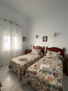 two beds in a room with a white bedspread at Tranvía Beach House in Chipiona