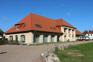 ein großes Gebäude mit orangefarbenem Dach in der Unterkunft Die Remise Marengo in Stolpe auf Usedom