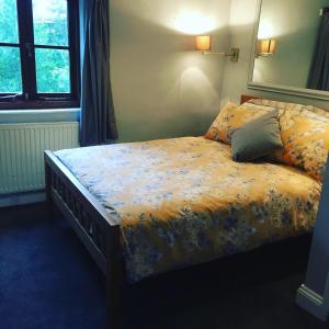 a bedroom with a bed with a floral comforter at Cricketers Cottage B&B in Kent
