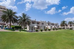 Radisson Blu Hotel & Resort, Al Ain في العين: منتجع فيه نخل وساحة خضراء