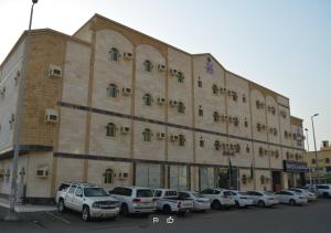 a large building with cars parked in a parking lot at Hmm Serviced Apartments in Al Kura