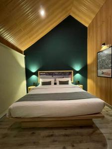 a bedroom with a large bed with a blue wall at LOKAL Rooms x Hunza (5 Peaks) in Baltit