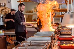a man cooking food in a kitchen with fire at Star Beach Village & Water Park in Hersonissos