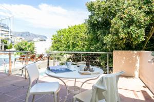 a table and chairs on a balcony with a view of the water at Camps Bay Village - Beach Studios in Cape Town