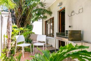 two white chairs sitting on a patio with plants at Camps Bay Village - Beach Studios in Cape Town