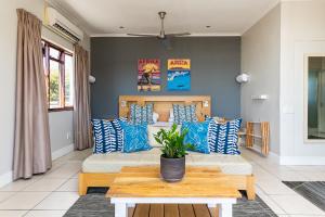 a living room with a couch with blue and white pillows at Camps Bay Village - Beach Studios in Cape Town