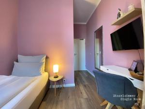 een kamer met een bed, een bureau en een televisie bij Amaroo - Gästehaus Potsdam “Charlottenhof” in Potsdam