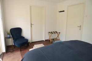 a bedroom with a blue bed and a chair at AaBenB appartement in Tilburg