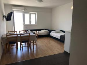a room with a table and chairs and two beds at Apartmani Silvano in Murter