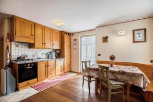 a kitchen with wooden cabinets and a table with chairs at Appartamento Le Coccinelle in Varena