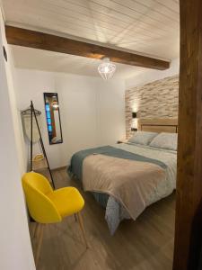 a bedroom with a bed and a yellow chair at Apartamentos Rurales Calleabajo - 3 Estrellas in Hervás