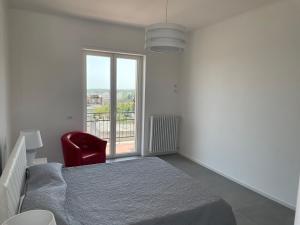 a bedroom with a bed and a red chair and a window at La casa di Zoe in Ceglie Messapica