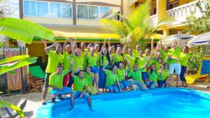 een groep mensen in groene shirts die naast een zwembad poseren bij Hôtel Restaurant Coco Lodge Majunga in Mahajanga