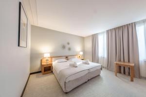 ein Schlafzimmer mit einem weißen Bett und einem großen Fenster in der Unterkunft Hôtel Le Picardy in Saint-Quentin