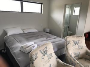 a bedroom with a bed and two chairs at Stylish Space in Twizel