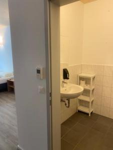 a bathroom with a white sink and a room at Campus Ferlach in Ferlach