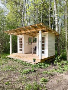 a small white shed with a deck in the woods at Hiiumaa Tiglu in Hiiumaa