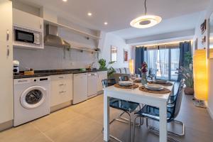 a kitchen with a table with chairs and a sink at Edificio Santiago by Plaza Mayor Apartamentos in Valladolid