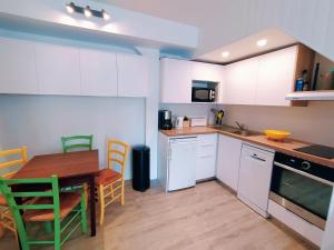 uma cozinha com armários brancos e uma mesa e cadeiras em Lalanne Btz, Duplex Jardinet près de la Plage em Biarritz