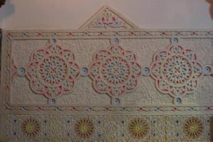 a white wall with a floral design on it at Riad Malak in Fez