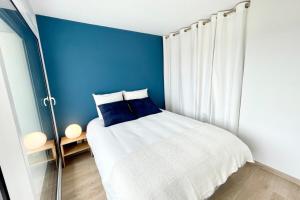 um quarto com paredes azuis e uma cama branca com almofadas azuis em T3 Neuf Archi Cocooning - Terrasse - Face à la mer em Ploemeur