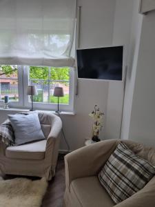 a living room with a couch and a flat screen tv at Les Trois Voiliers - mit Sauna in Juist