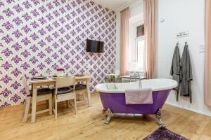 ein Badezimmer mit einer lila Badewanne und einem Tisch in der Unterkunft Elegant Coziness in Budapest