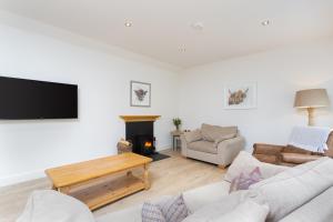 sala de estar con TV y chimenea en Railway Cottage, Newtyle en Newtyle