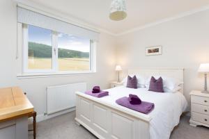 ein Schlafzimmer mit einem großen weißen Bett mit lila Handtüchern darauf in der Unterkunft Railway Cottage, Newtyle in Newtyle