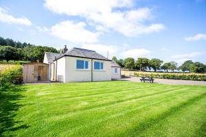 uma casa com um grande relvado em frente em Railway Cottage, Newtyle em Newtyle