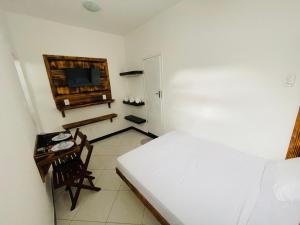 a bedroom with a bed and a table and a television at Kitnet encantadora, equipada, conforto no centro in Caratinga