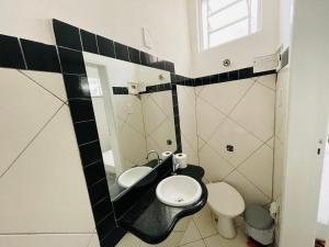 a bathroom with a sink and a toilet and a mirror at Kitnet encantadora, equipada, conforto no centro in Caratinga