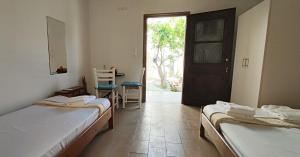 a room with two beds and a door and a table at Platia Studios in Matala