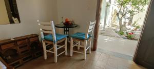 ein Esszimmer mit 2 Stühlen, einem Tisch und einem Fenster in der Unterkunft Platia Studios in Matala