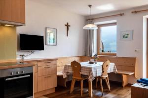eine Küche mit einem Tisch mit Stühlen und einem Kreuz an der Wand in der Unterkunft App Schlern Winklerhof in Villanders