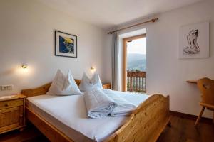 Schlafzimmer mit einem weißen Bett und einem Fenster in der Unterkunft App Schlern Winklerhof in Villanders