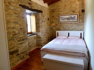 a bedroom with a bed and a brick wall at Casita feliz entre montañas y cerca del mar in Trabada