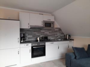 HageにあるFerienwohnung Phamの白いキャビネットと青いソファ付きのキッチンが備わります。 +24枚の写真