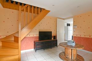 a living room with a television and a staircase at La Petite Maison Blanzy in Blanzy