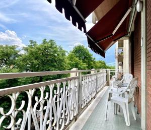 a balcony with white chairs and a table on it at Domus Fersina in Trento